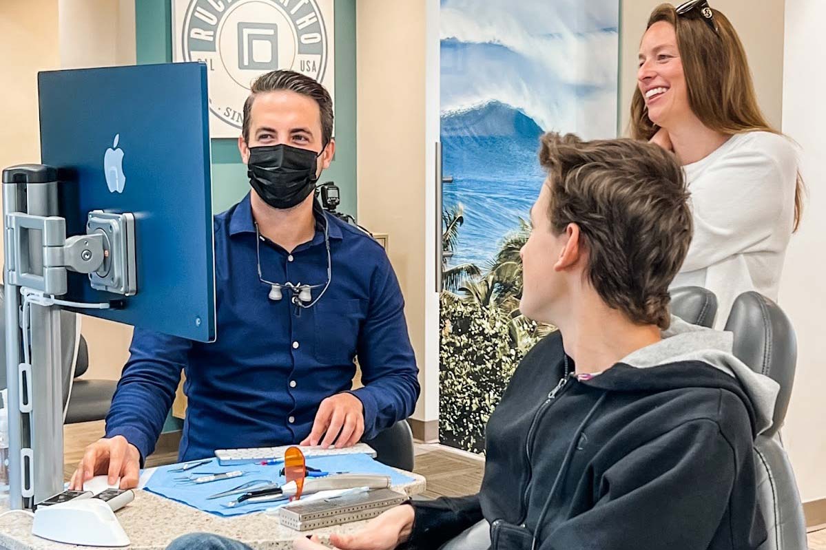 Dr. Rucker reviewing treatment images with a teenage patient and parent at Rucker Orthodontics